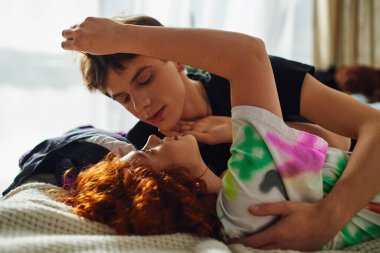 Çekici, sevgi dolu, samimi giysiler içinde bir çift yatakta birlikte yatarken öpüşmeye hazırlanıyor.