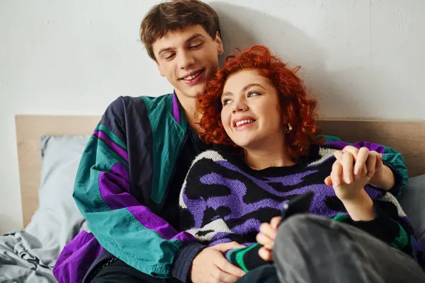 stock image joyous good looking couple in vibrant stylish attires hugging and laughing while in bed at home