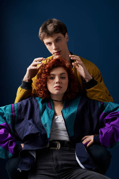 модная красивая пара в яркой стильной одежде, обнимающая с любовью и смотрящая в камеру