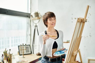 A woman holds a paintbrush and palette. clipart