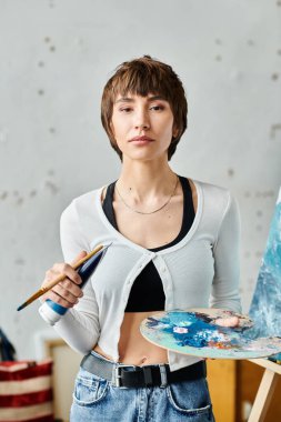 Woman holding paintbrush and palette. clipart