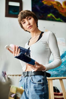 Bir odada elinde boyayla duran bir kadın..