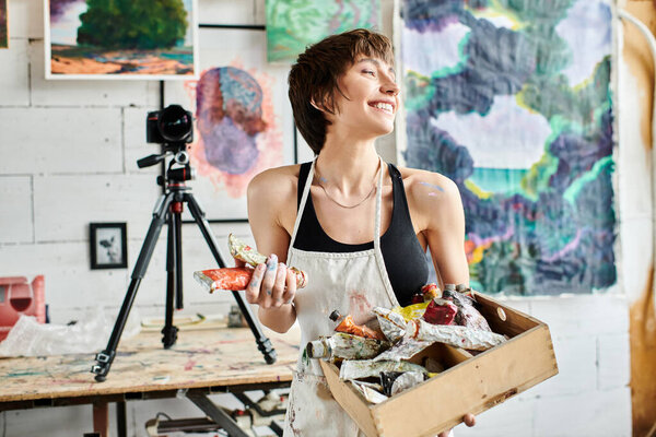 Женщина держит коробку с краской перед камерой.