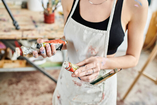 Woman wearing apron holding can of paint.