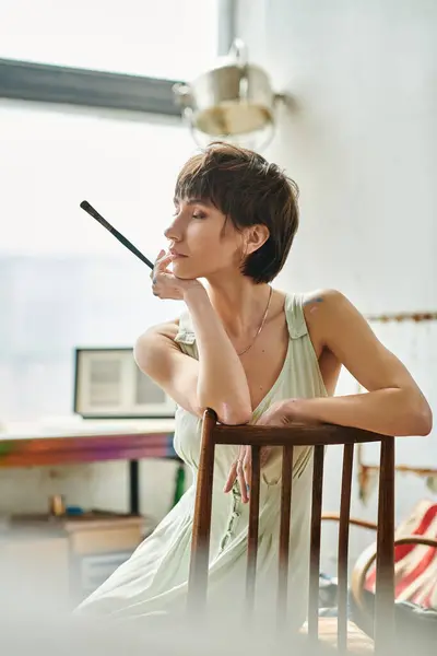 stock image A woman in a chair, deep in thought with hand on chin.