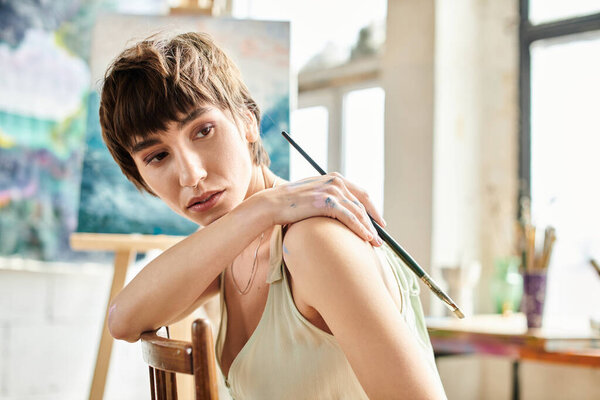 Женщина, сидящая в кресле, держа кисть.