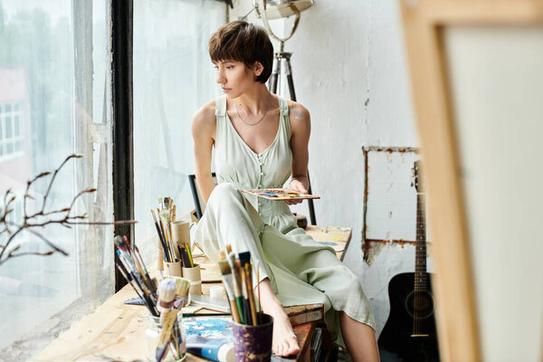 Женщина мирно сидит в кресле, держа палитру.