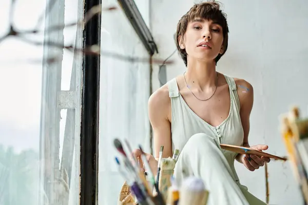 stock image A woman sitting, delicately holding a paintbrush.