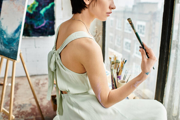 A woman in a white dress holds a paintbrush.