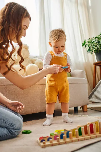 stock image A young woman engaged in play with her toddler daughter in a cozy living room, creating happy memories together.