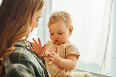 Genç bir anne, bebeğini kucağında tutarak samimi anlarında sevgi ve sıcaklık saçar..