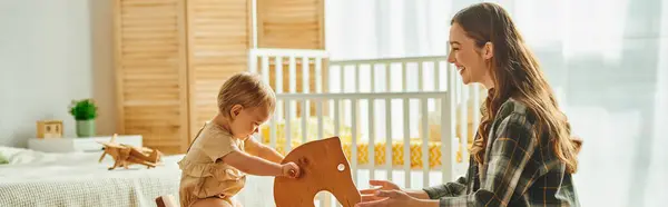 Young Girl Joyfully Plays Wooden Rocking Horse While Her Mother — Stock Photo, Image