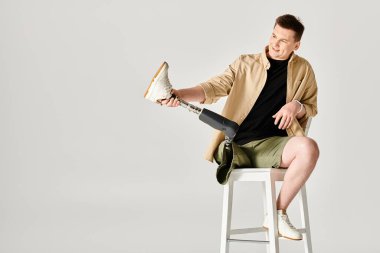 Protez bacaklı yakışıklı bir adam taburede oturuyor..