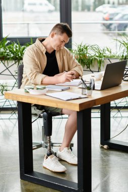 A handsome businessman with a prosthetic leg working on a laptop at a table. clipart