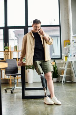 Ofiste duran protez bacaklı yakışıklı bir işadamı telefonla konuşuyor..