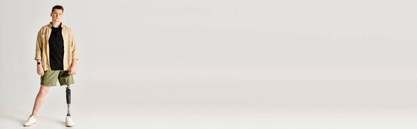 Стильный мужчина с протезной ногой активно позирует в черной рубашке и зеленых шортах.