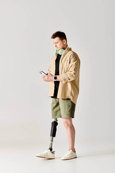 Красивый мужчина с протезной ногой в коричневой куртке использует смартфон..