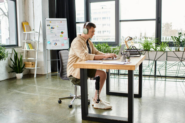 Красивый бизнесмен с протезной ногой сидит за столом в наушниках.
