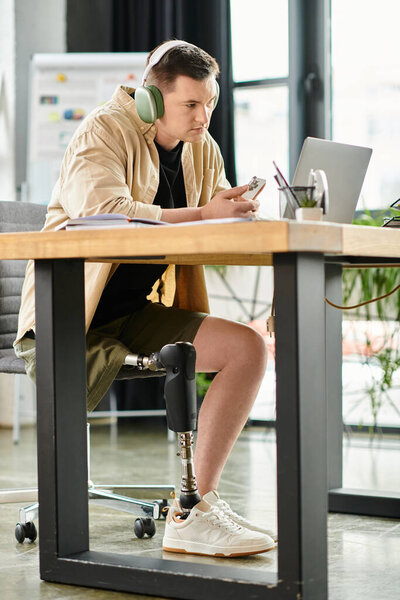 Красивый бизнесмен с протезной ногой сидит за столом в наушниках.
