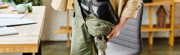 Красивый бизнесмен с протезной ногой, стоящий перед столом.