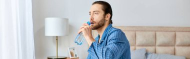 A handsome man in a blue attire drinking water. clipart