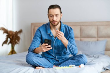 Man sitting on bed, focused on cell phone screen, morning light illuminating room. clipart