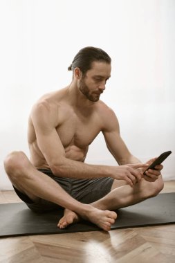 Yakışıklı adam, evde cep telefonu kullanırken huzur içinde yoga yapıyor..