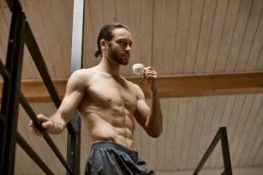 Shirtless man holding coffee in his hand during morning routine. clipart