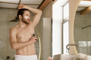 Gömleksiz adam aynanın önünde deodorant kullanıyor. Günlük rutinin bir parçası..