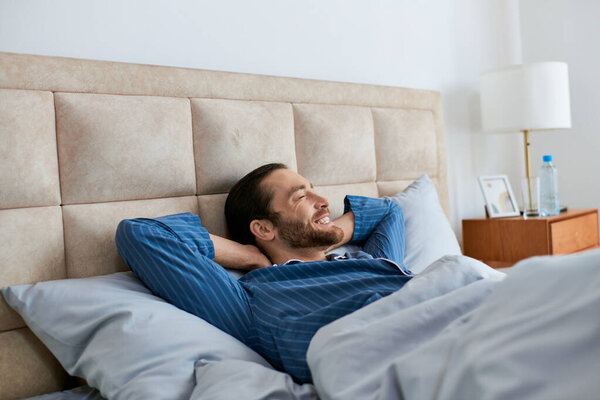 A man peacefully lays in bed with his head resting on the pillow.