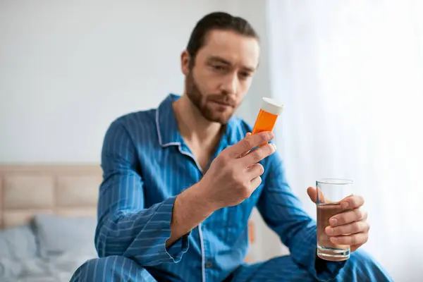stock image Handsome man in yoga pose seated on bed with glass in hand.
