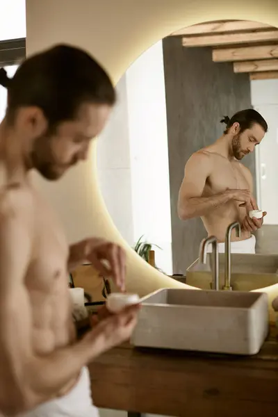 stock image Man grooming in bathroom mirror, applying skincare.