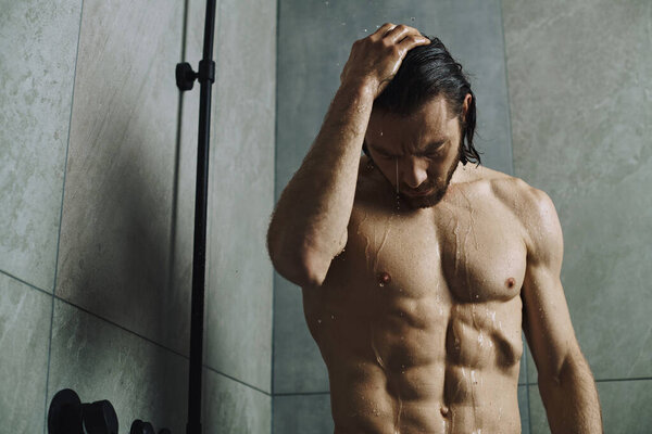 Мужчина без рубашки стоит перед душем, готовится к своему дню с рутиной по уходу за кожей.