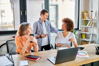 Group of diverse, hardworking women discussing strategy at a wooden table. clipart