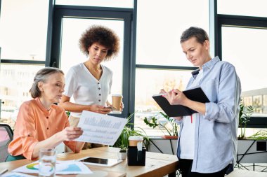 Diverse group of hard-working businesswomen sharing ideas around a table in a coworking space. clipart