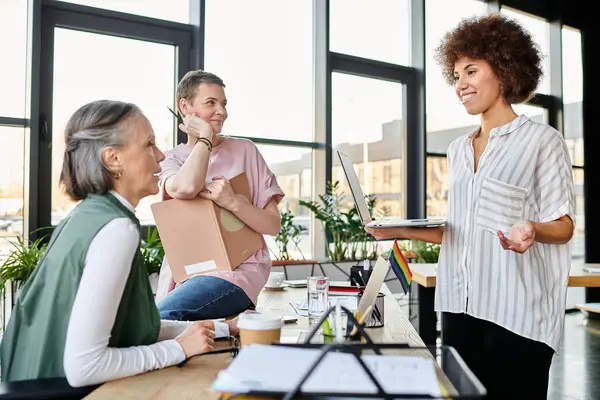 stock image Hardworking, diverse women gathered around a table, collaborating in an office setting.