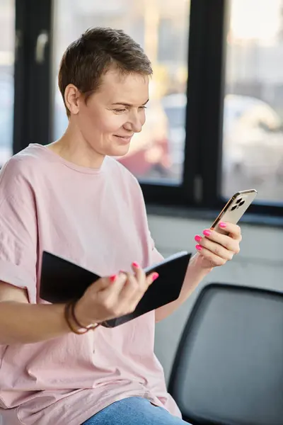 stock image A woman engrossed in her phone while in office.