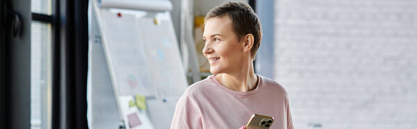 Предпочтительная деловая женщина в розовой рубашке смотрит в окно.