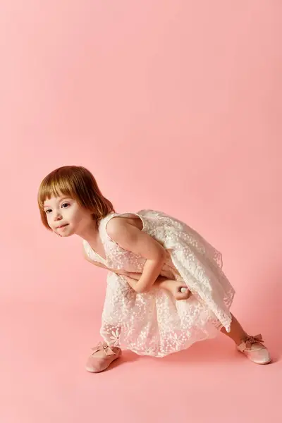 stock image A little girl in a white dress stands charmingly against a pink backdrop.