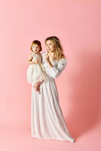 Woman White Dress Holds Baby Girl White Dress Pink Background — стоковое фото