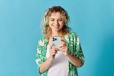 Kıvırcık saçlı genç kadın telefonda müzik dinlemekten hoşlanıyor..