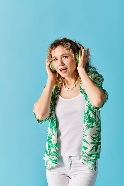 Кудрявая женщина наслаждается музыкой с наушниками на синем фоне.