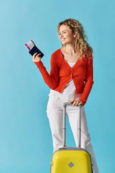 Stock image Woman posing with a yellow suitcase and holding passport and ticket.