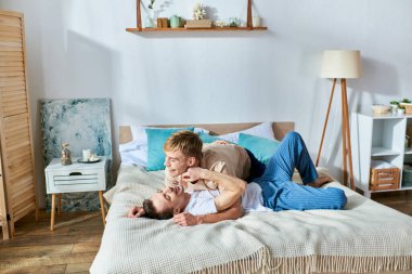 Gündelik giysiler içinde iki adam bir yatakta yatıyor.