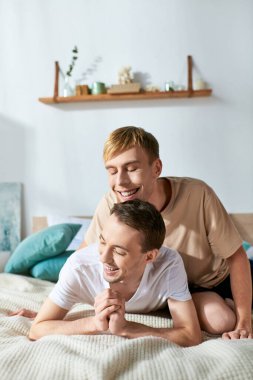 Two men cuddling on a bed in casual attire. clipart