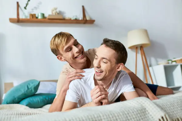 Stock image Two men lie together on a bed, sharing an intimate moment.