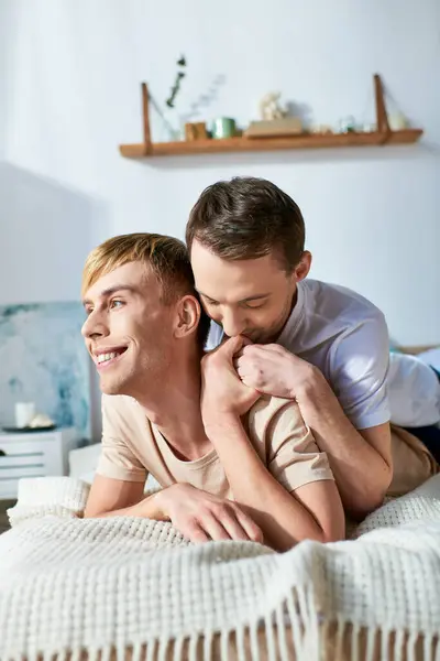 カジュアルな服装の2人の男性がベッドの上に一緒に横たわり 優しい瞬間を共有する — ストック写真