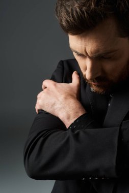 Siyah takım elbiseli bir adam elleri birbirine kenetlenmiş duruyor..