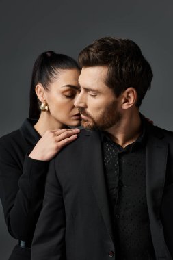 Şık bir erkek ve kadın birlikte durur, elbiseleriyle sevgi ve zarafet yayarlar..