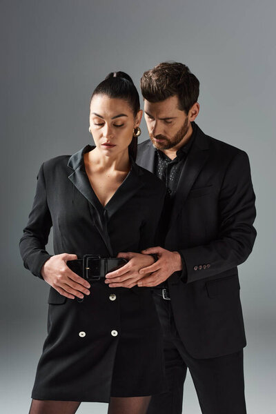 A man and a woman in elegant attire stand side by side, radiating love and grace.